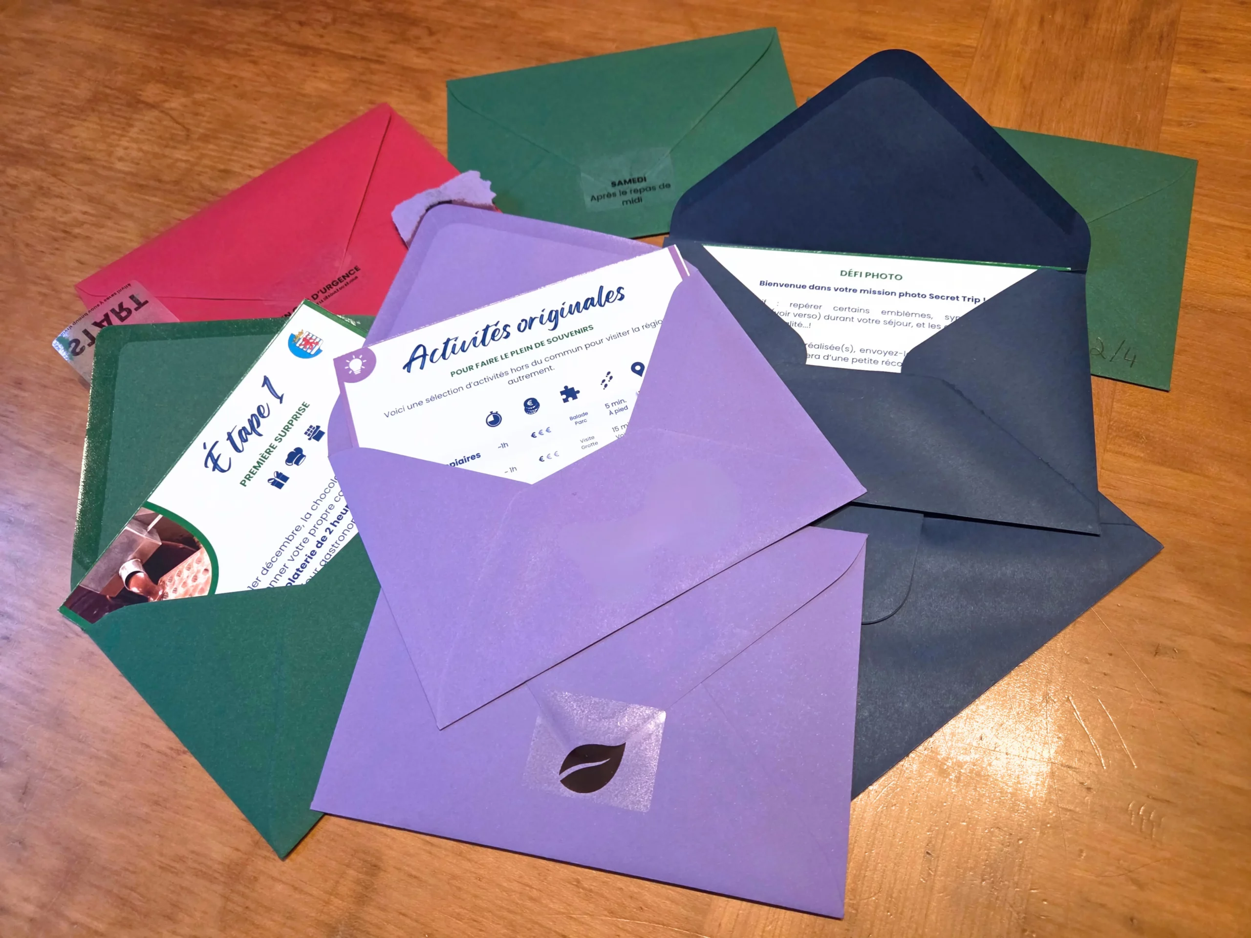 Enveloppes colorées Secret Trip ouvertes avec fiches voyage — vert, mauve, marine, rouge